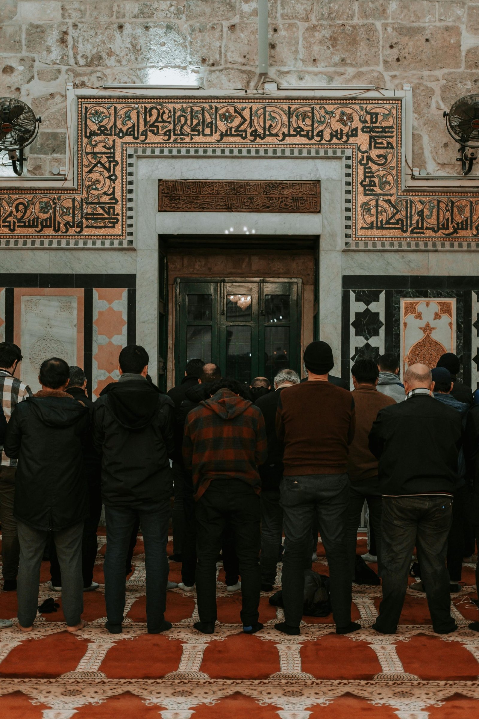 A group of men engaged in prayer inside a historic mosque in Jerusalem, showcasing Islamic architecture.