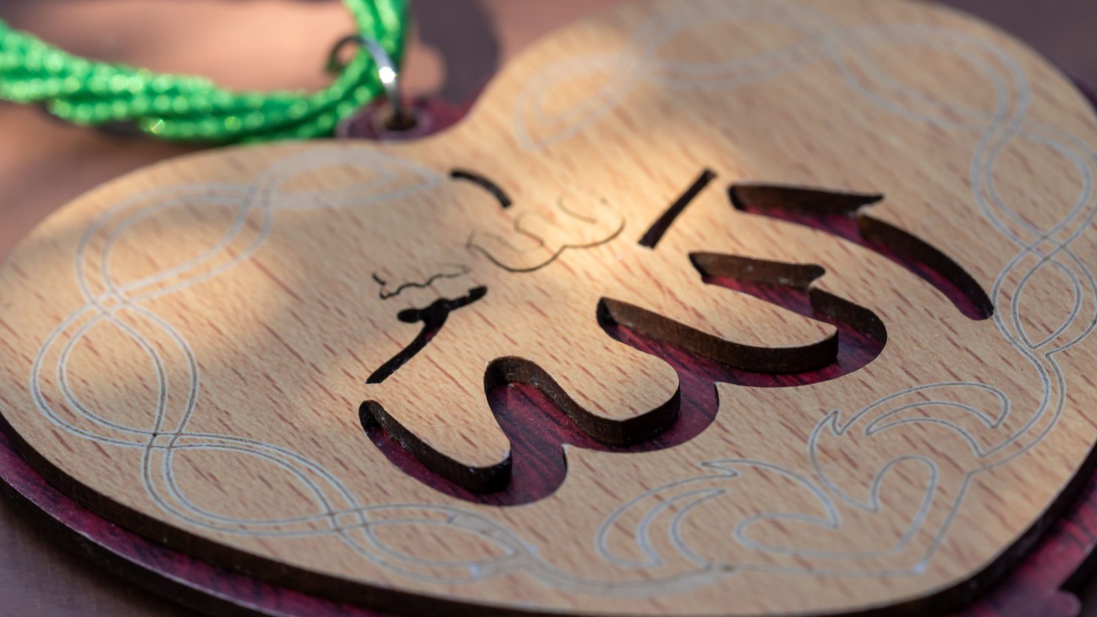 Heart-shaped pendant with Arabic calligraphy, symbolizing faith and decoration.